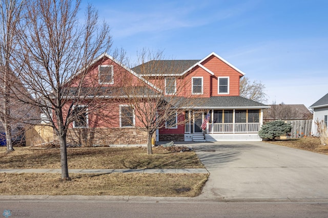 view of front facade featuring concrete driveway, a sunroom, and roof with shingles