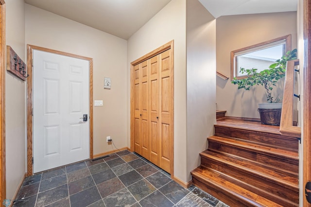 entryway with stairway, stone tile floors, and baseboards