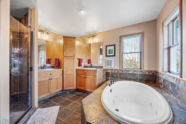 full bath featuring a sink, two vanities, a jetted tub, and a stall shower