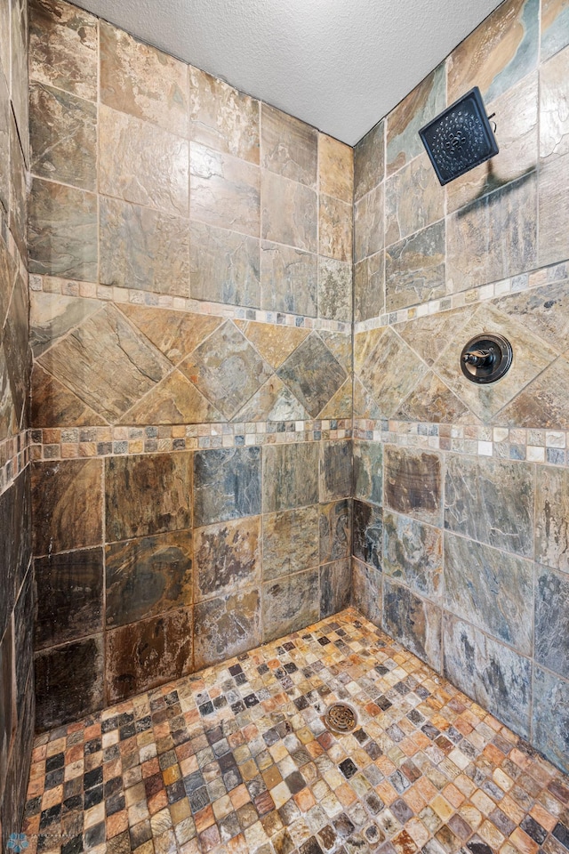 full bathroom with a tile shower and a textured ceiling