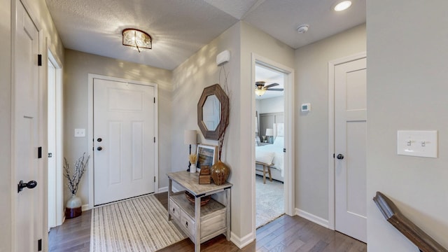 entryway featuring ceiling fan, dark wood-type flooring, baseboards, and a textured ceiling