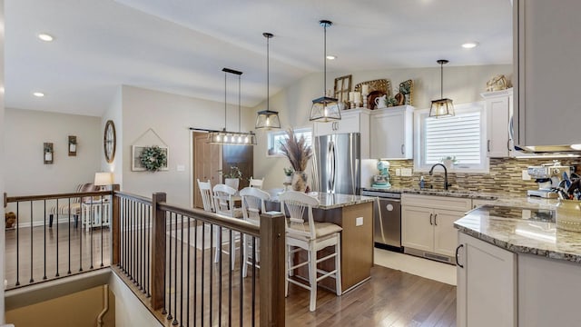 kitchen featuring light stone countertops, wood finished floors, appliances with stainless steel finishes, and a sink