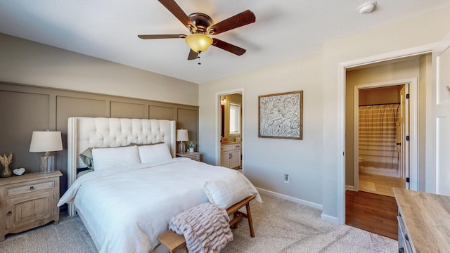 carpeted bedroom featuring baseboards, ensuite bathroom, and ceiling fan