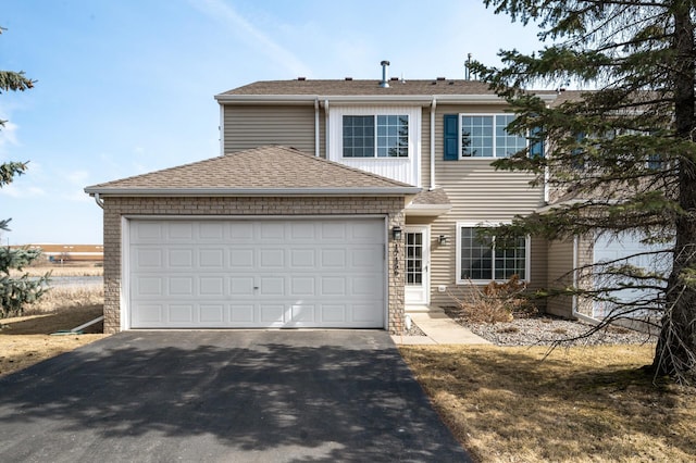 traditional-style home with driveway, an attached garage, and a shingled roof