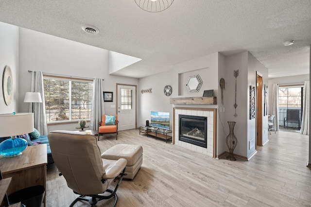 living room featuring a wealth of natural light, light wood-type flooring, visible vents, and a fireplace