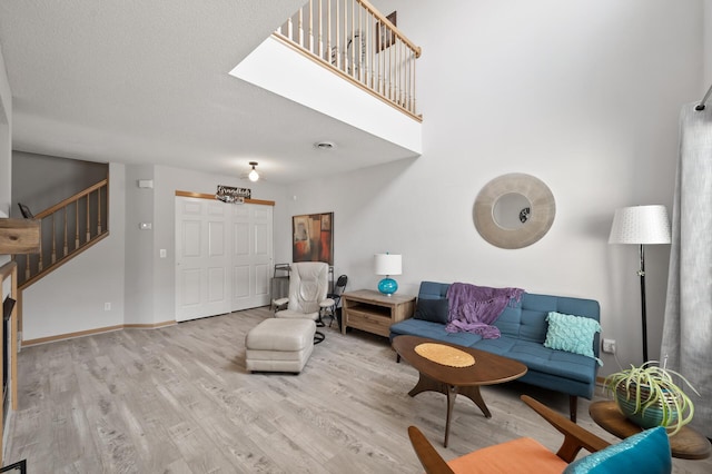 living area featuring baseboards, wood finished floors, and stairs