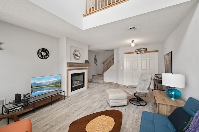 living room with stairway, wood finished floors, visible vents, baseboards, and a fireplace