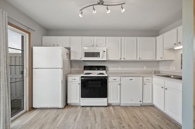 kitchen with light wood finished floors, white appliances, white cabinetry, and light countertops