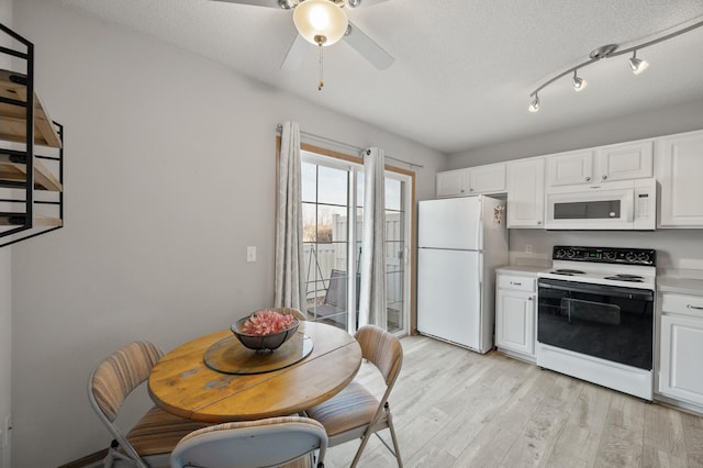 kitchen with white appliances, white cabinetry, light wood-type flooring, and a ceiling fan