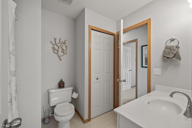 full bathroom with toilet, a textured ceiling, vanity, and baseboards