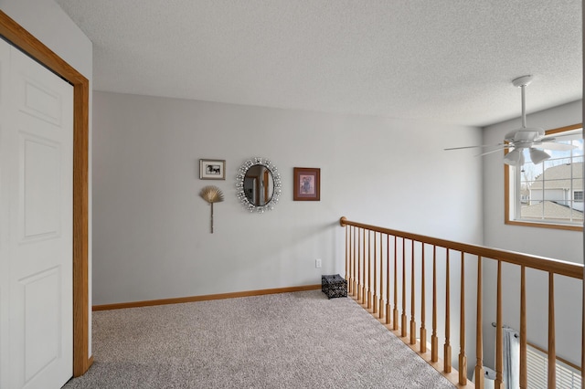 hallway featuring a textured ceiling, baseboards, and carpet floors