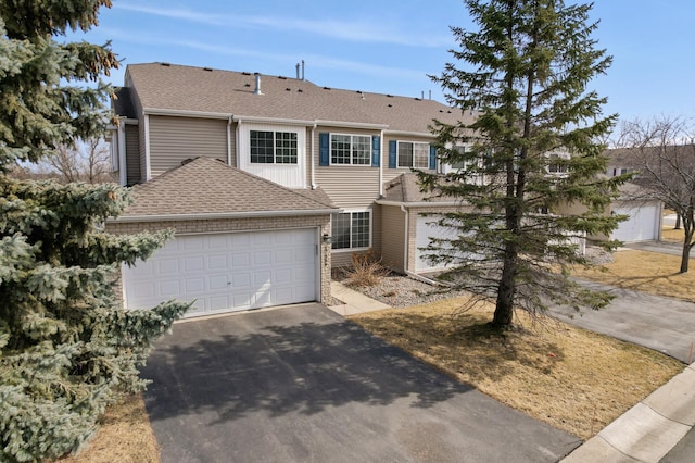 view of front of house with a garage, roof with shingles, and driveway