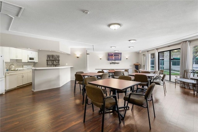 dining room featuring visible vents, a textured ceiling, and dark wood-style flooring