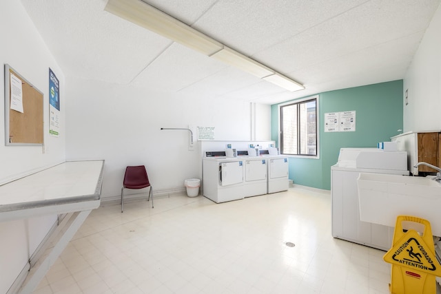 shared laundry area with washer and dryer, baseboards, tile patterned floors, and a sink