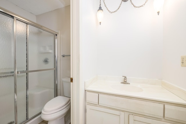 bathroom featuring vanity, a shower stall, and toilet