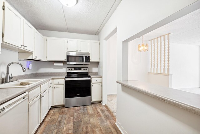 kitchen with a chandelier, light countertops, light wood-style flooring, appliances with stainless steel finishes, and a sink