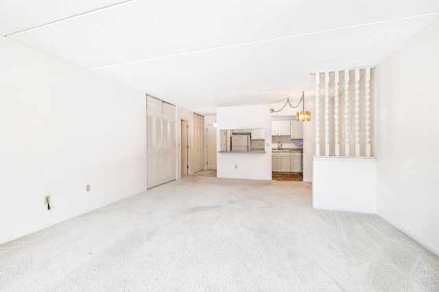 unfurnished living room featuring light colored carpet, baseboards, and a sink