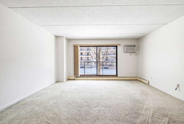 carpeted spare room with baseboards, a textured ceiling, an AC wall unit, and a textured wall