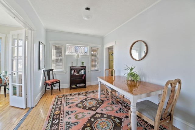 dining area with crown molding, light wood-style flooring, and baseboards