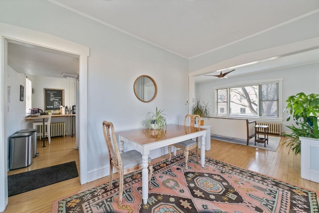 dining space with hardwood / wood-style flooring, radiator heating unit, crown molding, and baseboards