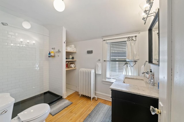 full bath featuring vanity, wood finished floors, radiator heating unit, a shower stall, and toilet