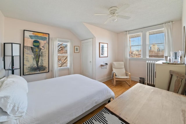 bedroom featuring wood finished floors, baseboards, radiator heating unit, ceiling fan, and a textured ceiling