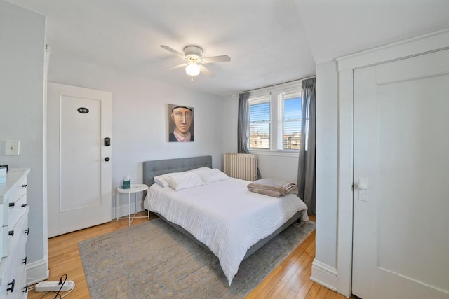 bedroom featuring radiator heating unit, light wood finished floors, and ceiling fan