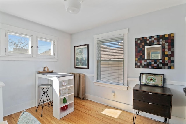 interior space featuring baseboards, light wood-style floors, and radiator heating unit