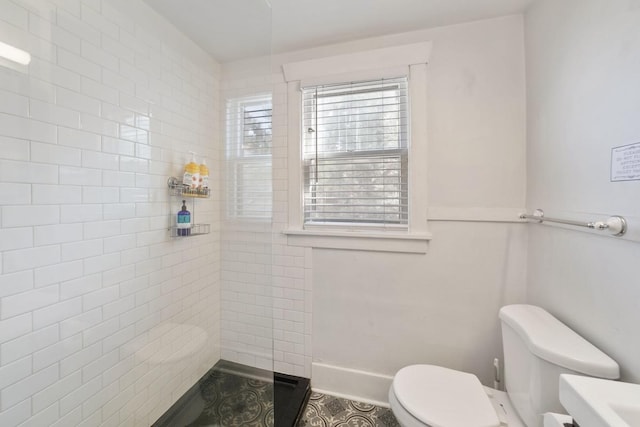 bathroom featuring tiled shower and toilet