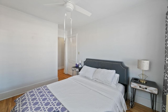 bedroom with ceiling fan, baseboards, and wood finished floors