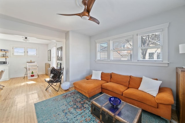 living area with light wood-style floors and a ceiling fan