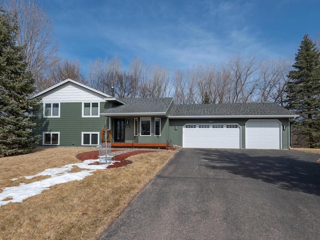 tri-level home featuring driveway, roof with shingles, a porch, and an attached garage