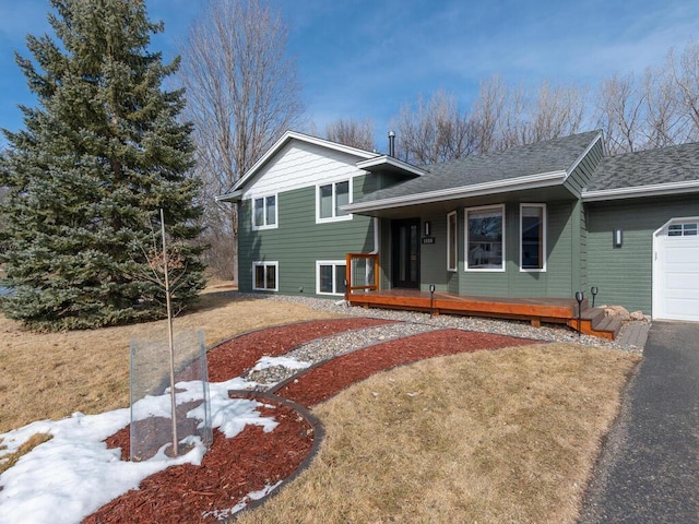 tri-level home with a porch, an attached garage, and driveway