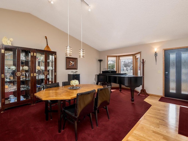 dining area with baseboards, lofted ceiling, a textured ceiling, and wood finished floors