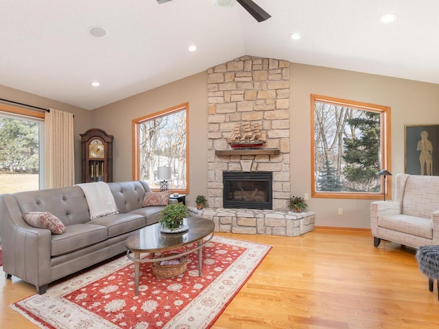 living area featuring baseboards, vaulted ceiling, a fireplace, wood finished floors, and a ceiling fan