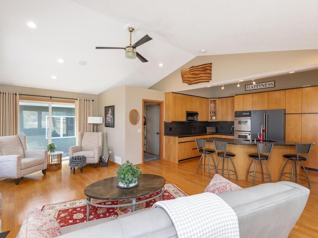 living area with baseboards, a ceiling fan, light wood-type flooring, and lofted ceiling