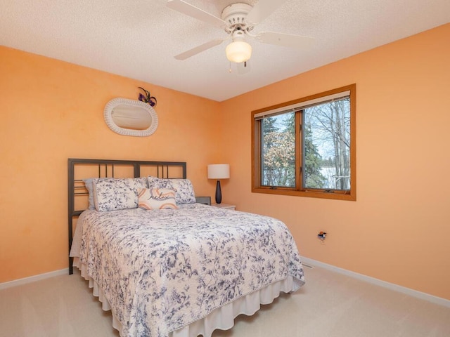 carpeted bedroom with a textured ceiling, baseboards, and a ceiling fan