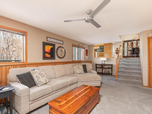 carpeted living area featuring stairs, a textured ceiling, and ceiling fan