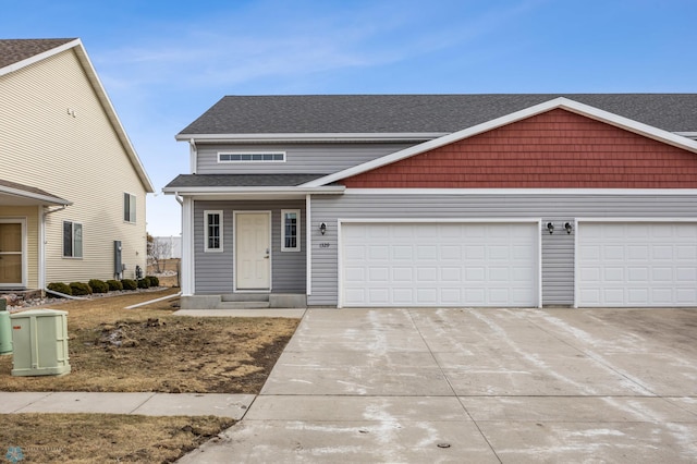 view of front of property featuring an attached garage, driveway, and a shingled roof