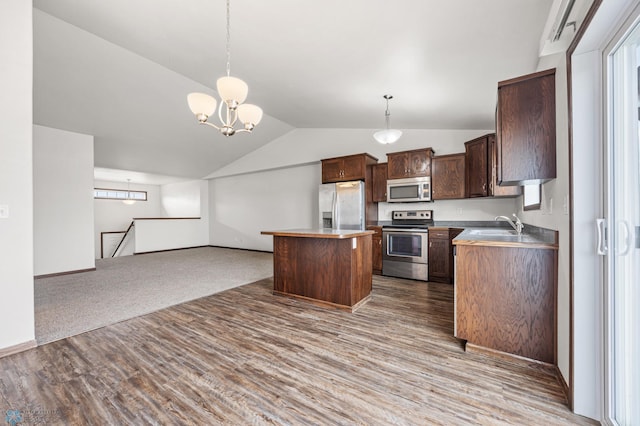 kitchen featuring a kitchen island, vaulted ceiling, appliances with stainless steel finishes, open floor plan, and a chandelier