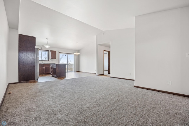 unfurnished living room with baseboards, vaulted ceiling, light carpet, an inviting chandelier, and a sink