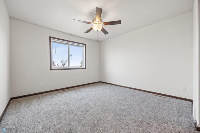 carpeted spare room featuring baseboards and ceiling fan