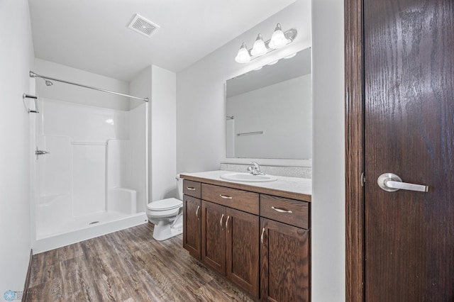 full bathroom featuring vanity, wood finished floors, visible vents, a shower, and toilet