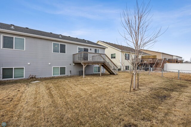 back of property featuring stairway, a lawn, a deck, and fence