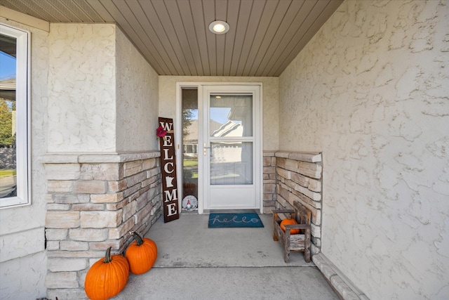 doorway to property featuring stucco siding and stone siding