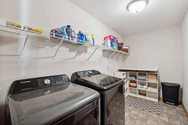 laundry room with laundry area, stone finish floor, baseboards, and separate washer and dryer