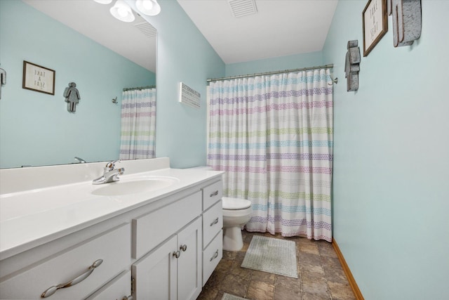 bathroom featuring vanity, baseboards, visible vents, stone finish floor, and toilet