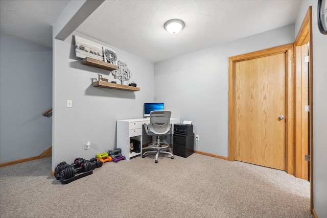 carpeted office space with a textured ceiling and baseboards