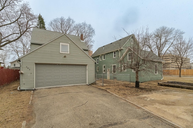view of side of property with a chimney, fence, an outbuilding, and a garage