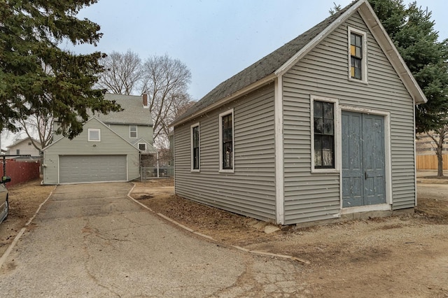 view of side of property featuring a detached garage, fence, and an outdoor structure